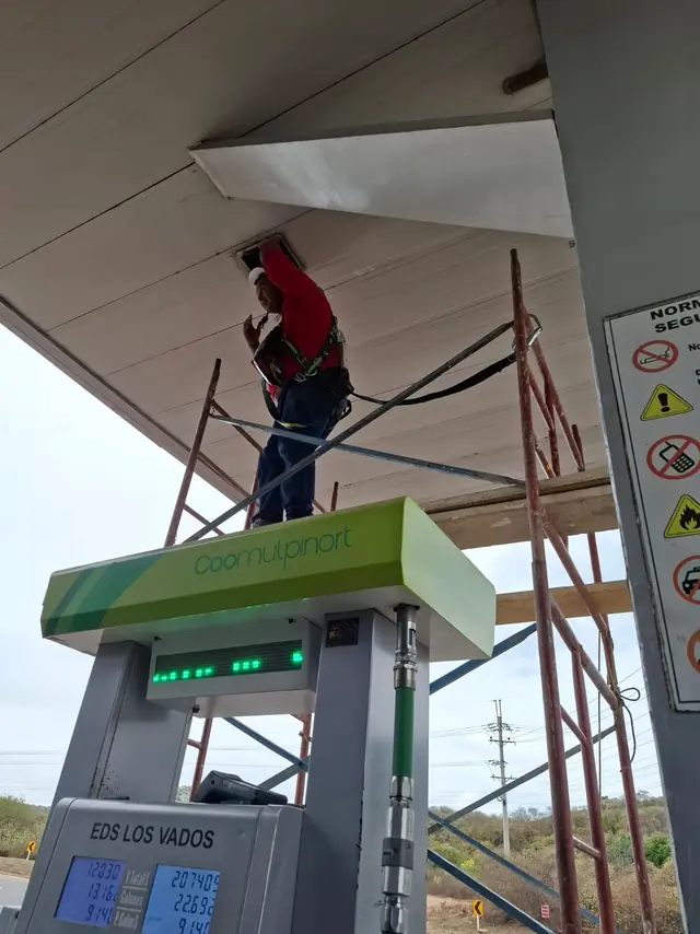 Técnico trabajando sobre andamio en el cielo raso de la marquesina, con arnés anclado